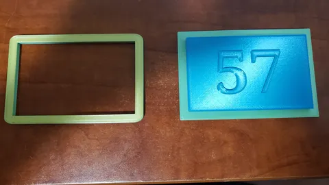 3D-printed 1957 Chevy dash clock filler plate with a raised 57 beside its trim bezel