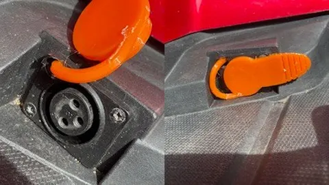 Orange 3D-printed flexible cover on a mobility scooter charging port, open and closed