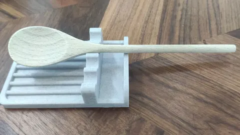 3D-printed kitchen spoon rest holding a wooden spoon over a ridged drip tray