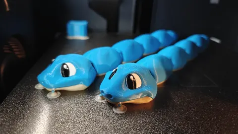 Two blue 3D-printed articulated snakes with big cartoon eyes